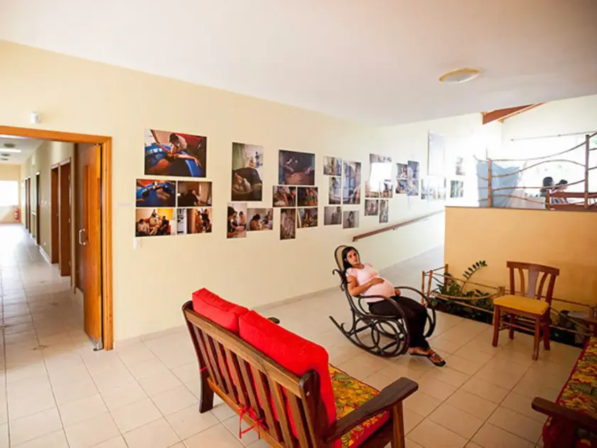 Une femme enceinte se repose sur une chaise berçante dans un couloir décoré de photos.