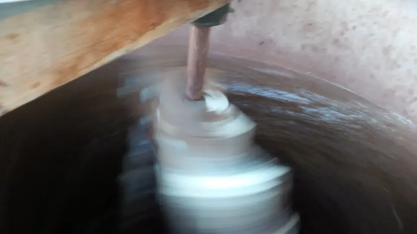 Un mélangeur en mouvement dans un récipient, créant des tourbillons de matière.
