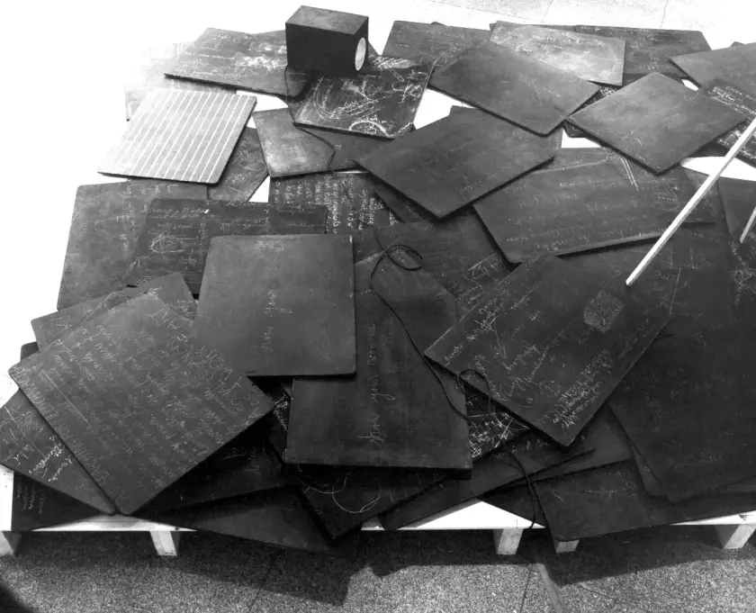 Un ensemble de tableaux noirs recouverts d'écritures et de dessins, disposés de manière désordonnée.