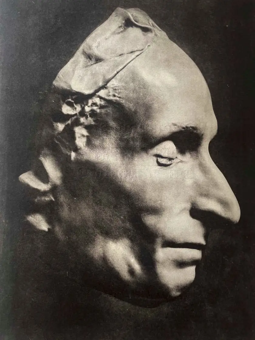 Un masque en plâtre représentant un visage humain de profil, avec des traits marqués et une texture détaillée.