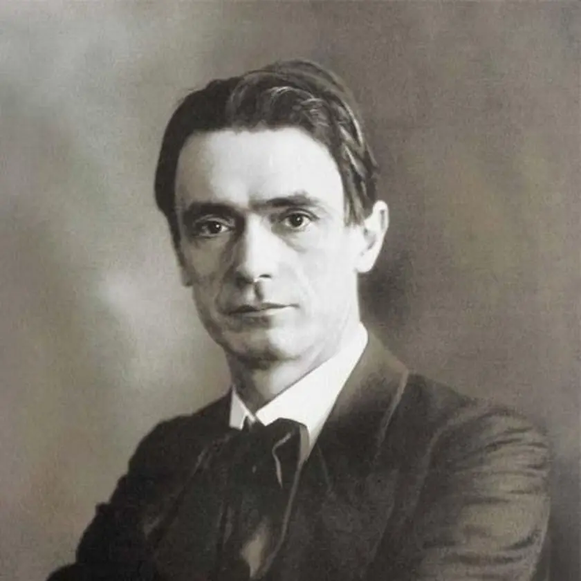 Portrait en noir et blanc d'un homme avec des cheveux bruns et une chemise blanche, portant un costume sombre.