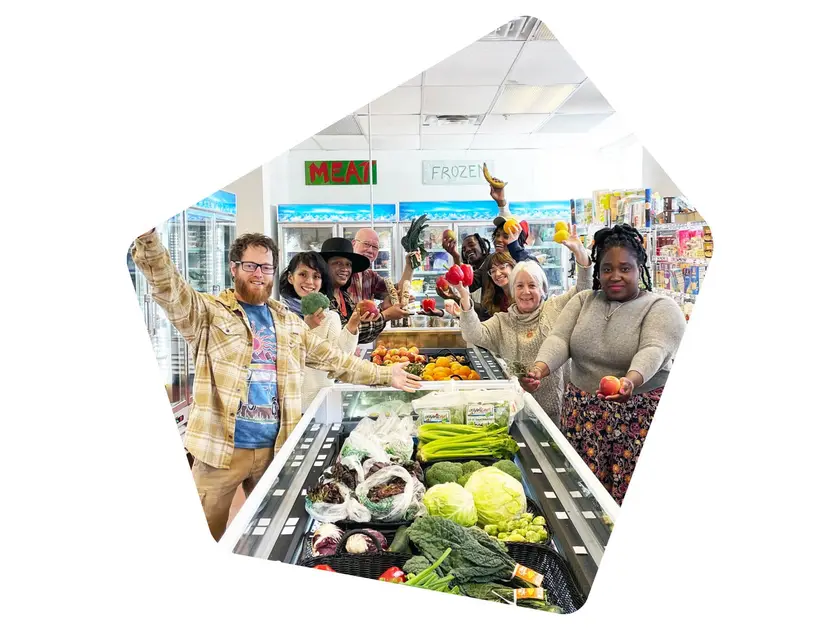 Un groupe de personnes souriantes dans un magasin, tenant des fruits et légumes frais.